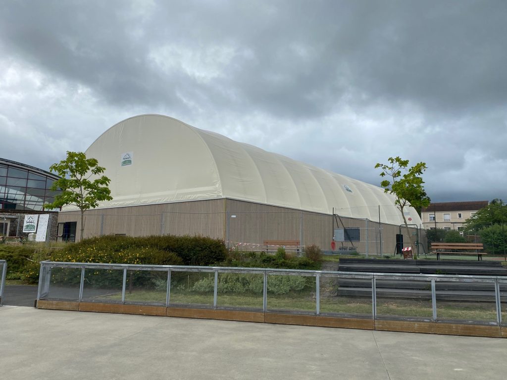 Court de tennis couvert par une couverture textile sur portiques en bois lamellé-collé – vue extérieure